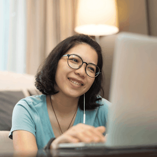 An online graduate student smiling while attending an online course on thier laptop